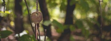 Ein Schlüssel mit der Aufschrift »Restore« an einer Kette hängend, im Hintergrund Wald.