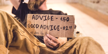 Guter Rat hat seinen Preis, muss aber nicht teuer sein. Eine sitzende Person die ein Schild hält mit der Aufschrift: Ratschlag 50 Cent, Guter Ratschlag 2 Euro,  schlechte Witze umsonst.
